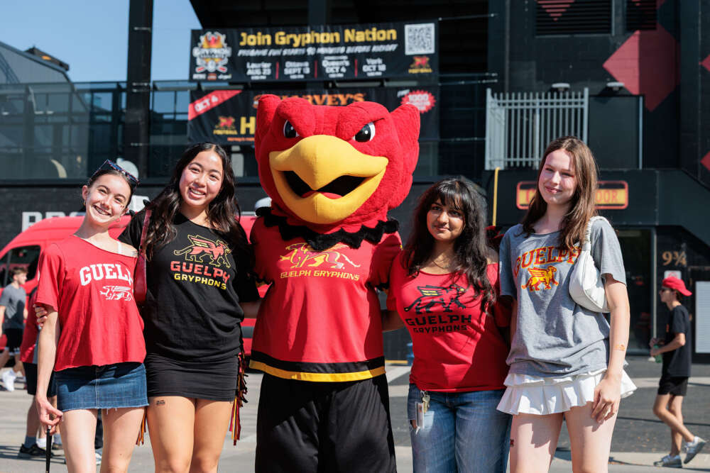 red mascot poses with people in front of football stadium