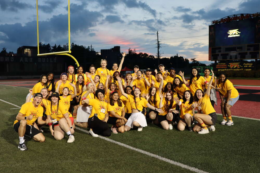 team dressed in yellow poses as group on football field