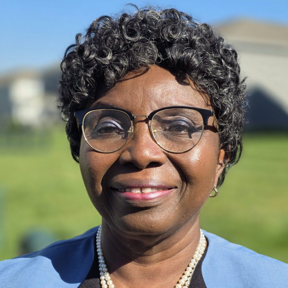 person in glasses and blue blazer poses for headshot
