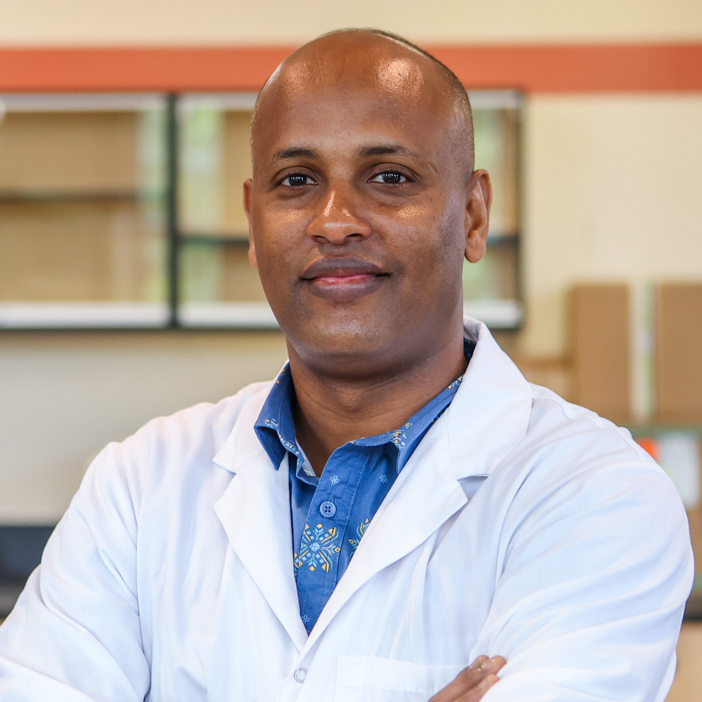 person in lab coat poses for headshot in lab