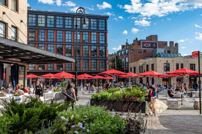 The meatpacking district, a large open square with red umbrellas in front of some buildings.