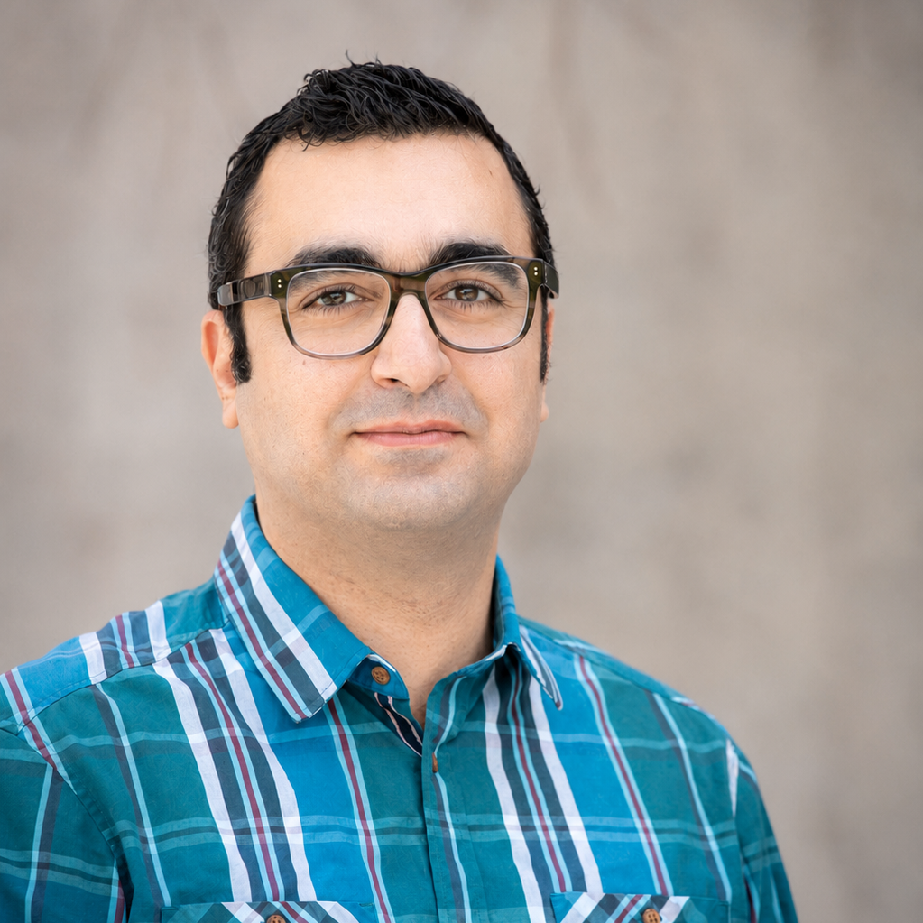 person in glasses and blue plaid poses for headshot