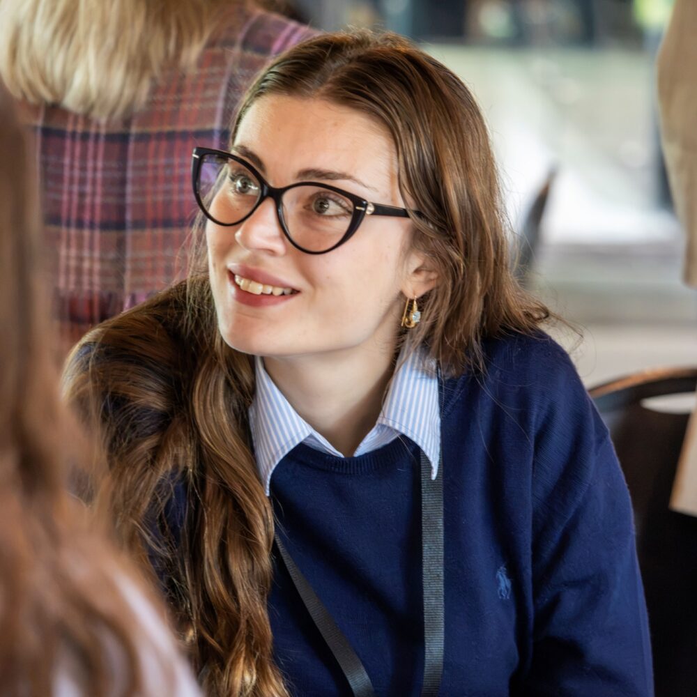 person in glasses sits at table in conference room