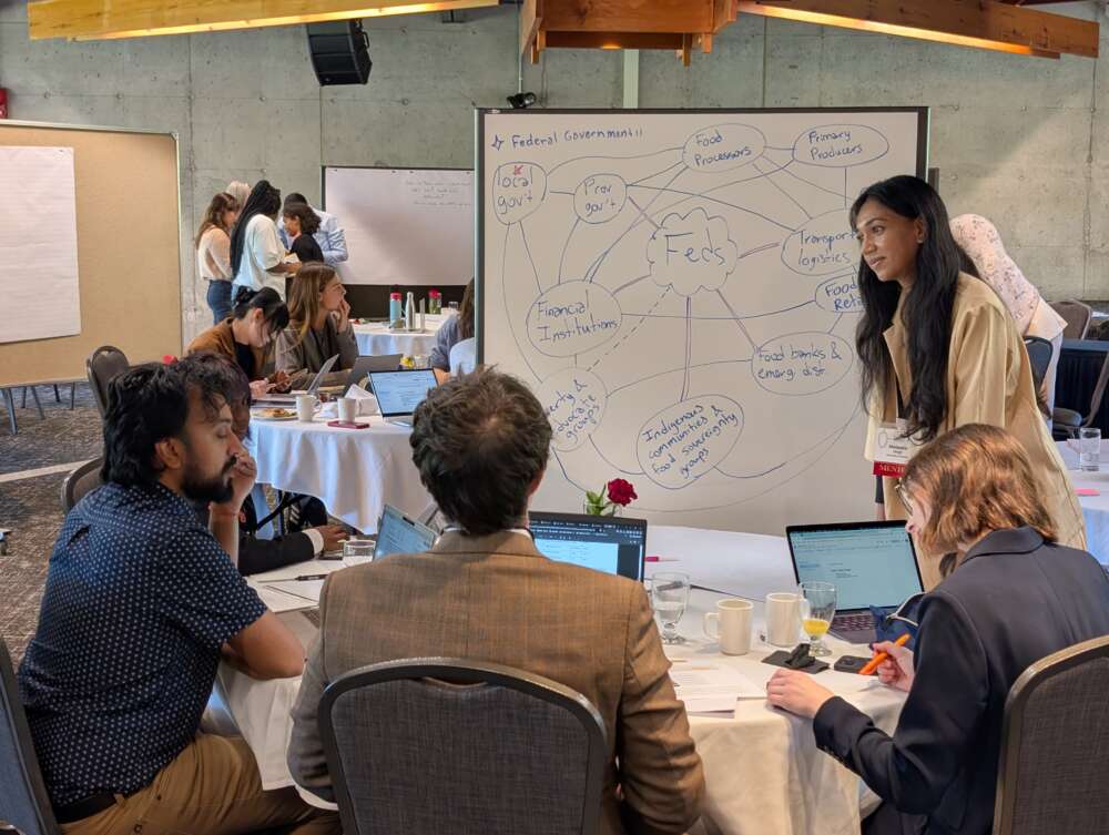 people sit at a round table in front of a white board