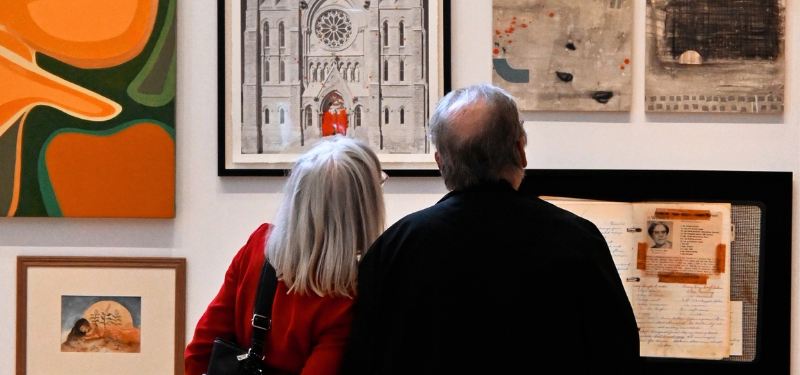 Two people look at a painting in a gallery.