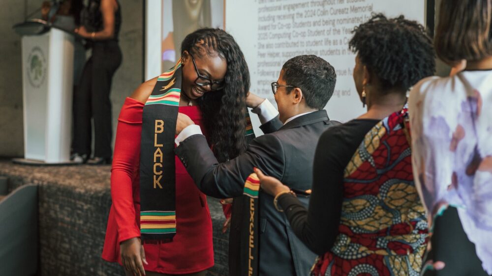 A person confers a stole onto a grad at a ceremony