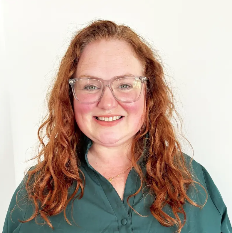 person in glasses and green shirt poses for headshot