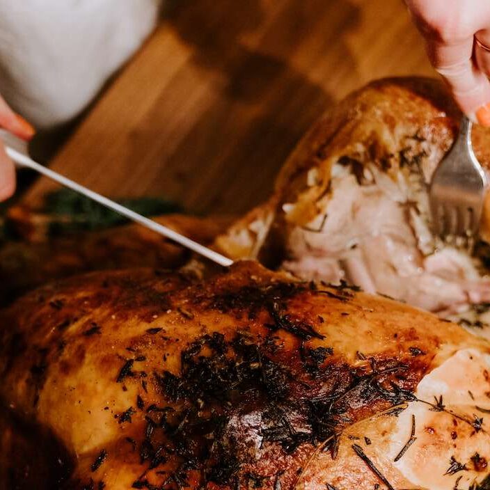 A person carves into a turkey.