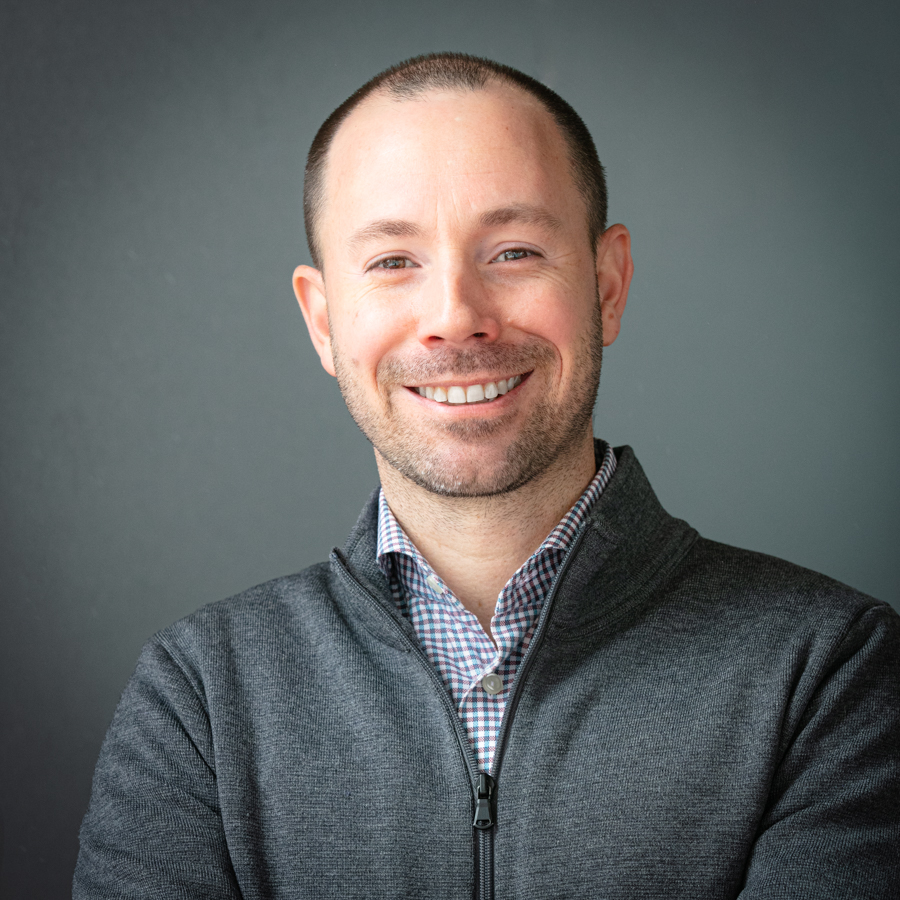 Dr. Philip Millar poses for a portrait against a grey backdrop