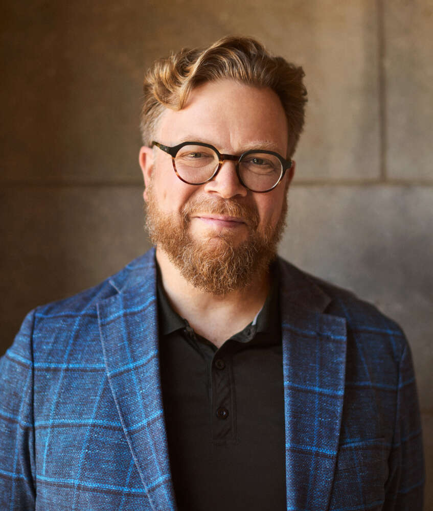 a professional portrait of a person standing against a stone wall