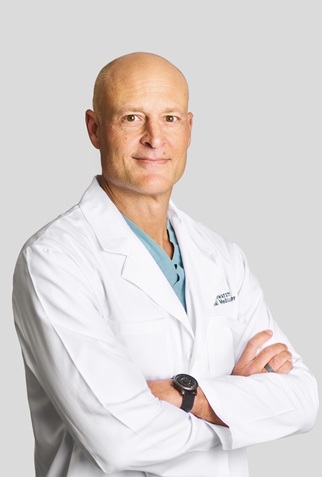 Headshot of Chick Weisse smiling, with arms crossed, wearing a lab coat.